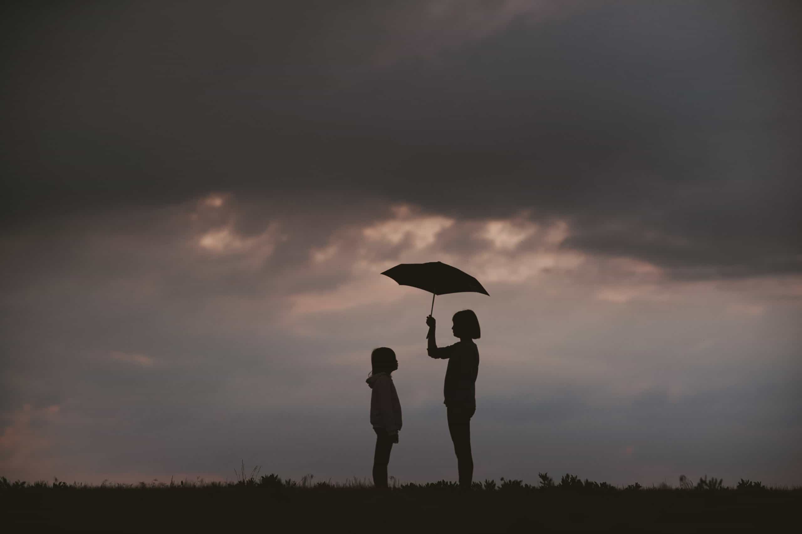 Two people standing with one holding umbrella