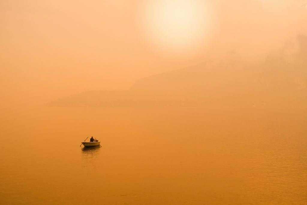 boat floating in sunset tinted ocean