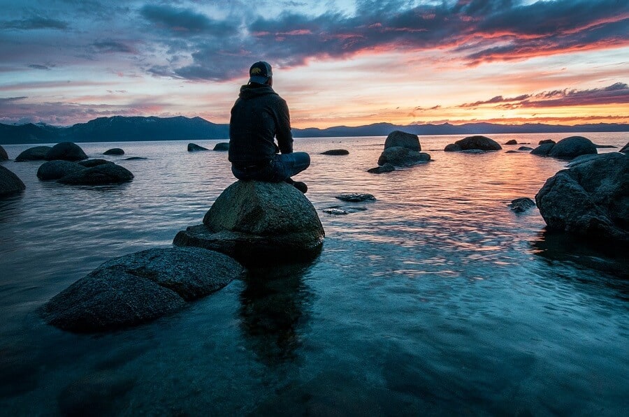 Being present and staying in the moment 2 man sitting on rock