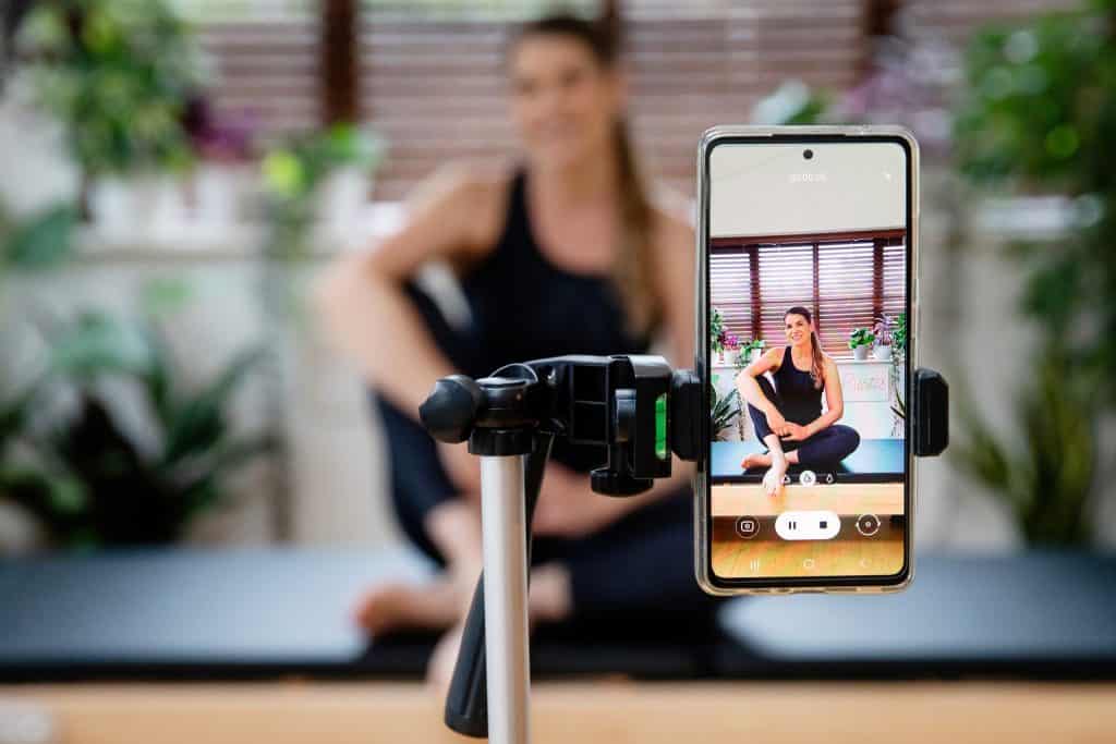 woman filming a postnatal pilates class