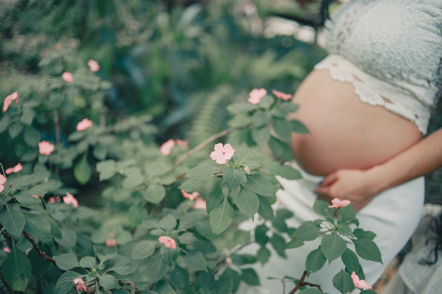 Pregnant woman behind leaves
