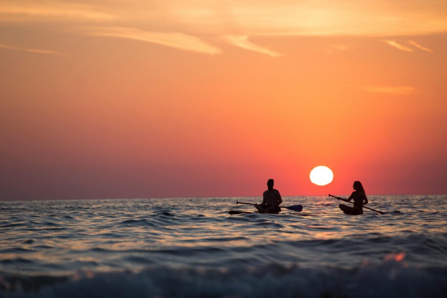 Why Do I Feel Lonely in My Relationship? 9 Silhouette of a couple paddleboarding on the ocean during a stunning sunset, capturing romance and adventure.