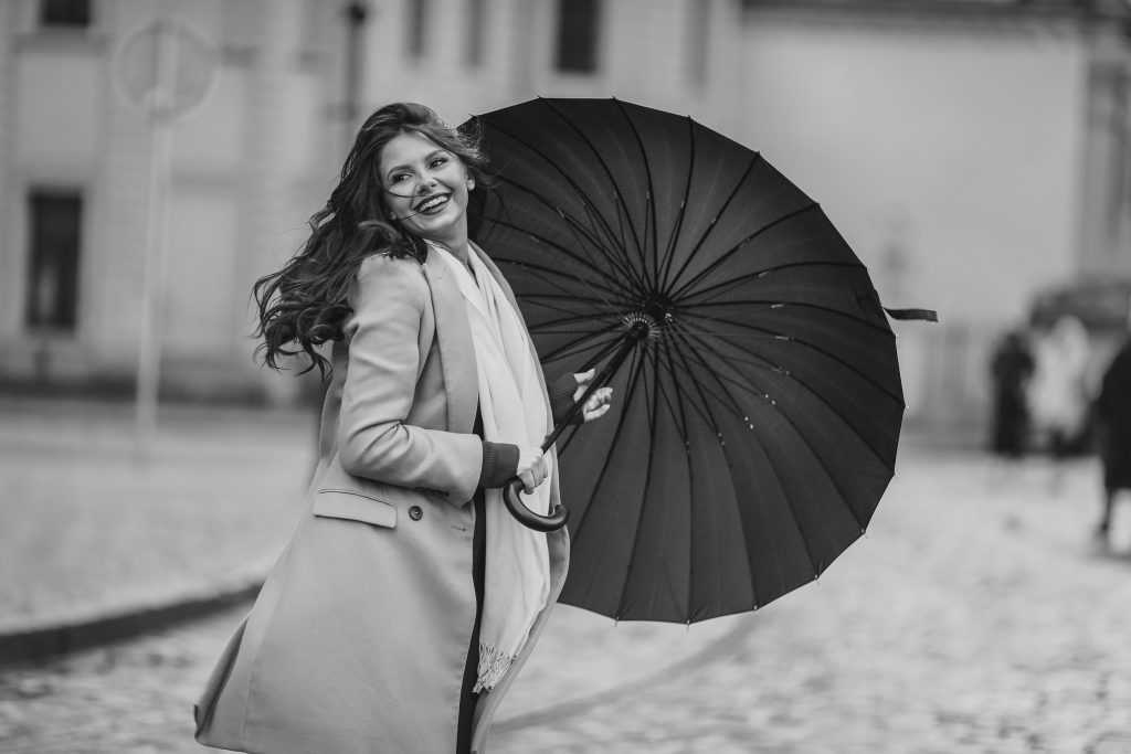 Stylish woman with umbrella, captured on city streets in black and white elegance.