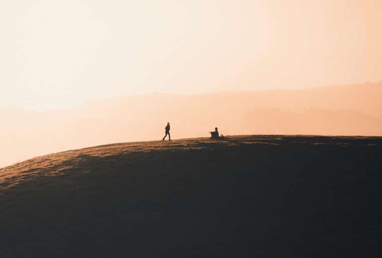 Silhouetted figures on a hilltop at sunrise evoke peace and relaxation.